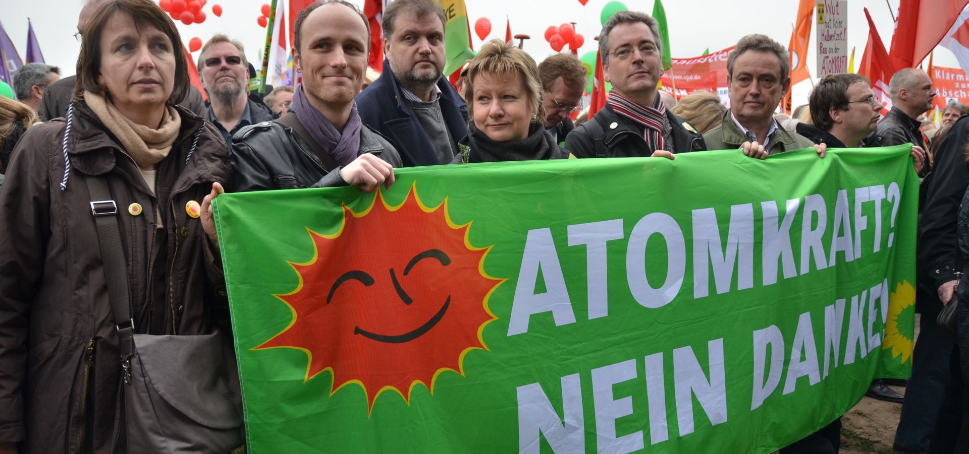 People are demonstrating and holding a banner which says "No to nuclear energy" in German.