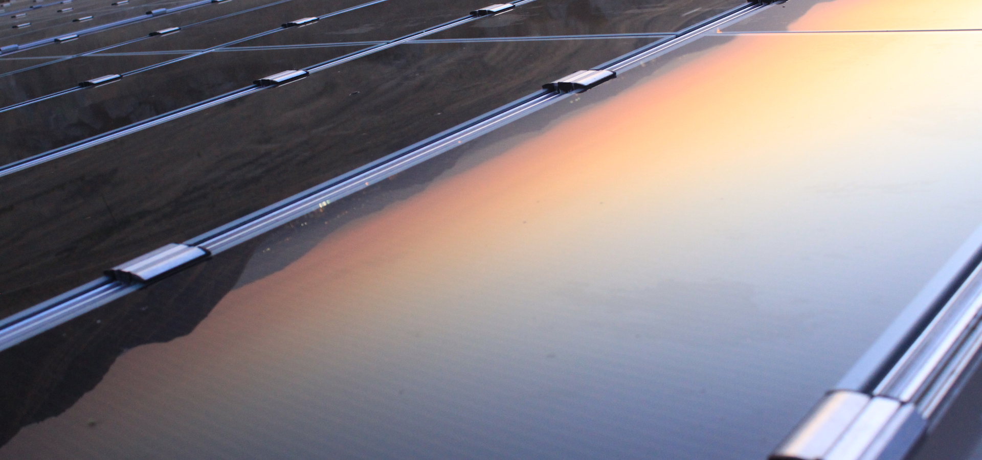 Solar panels reflecting mountains and sunset
