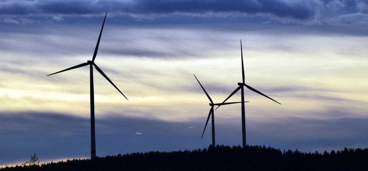 three windmills against a dark sky