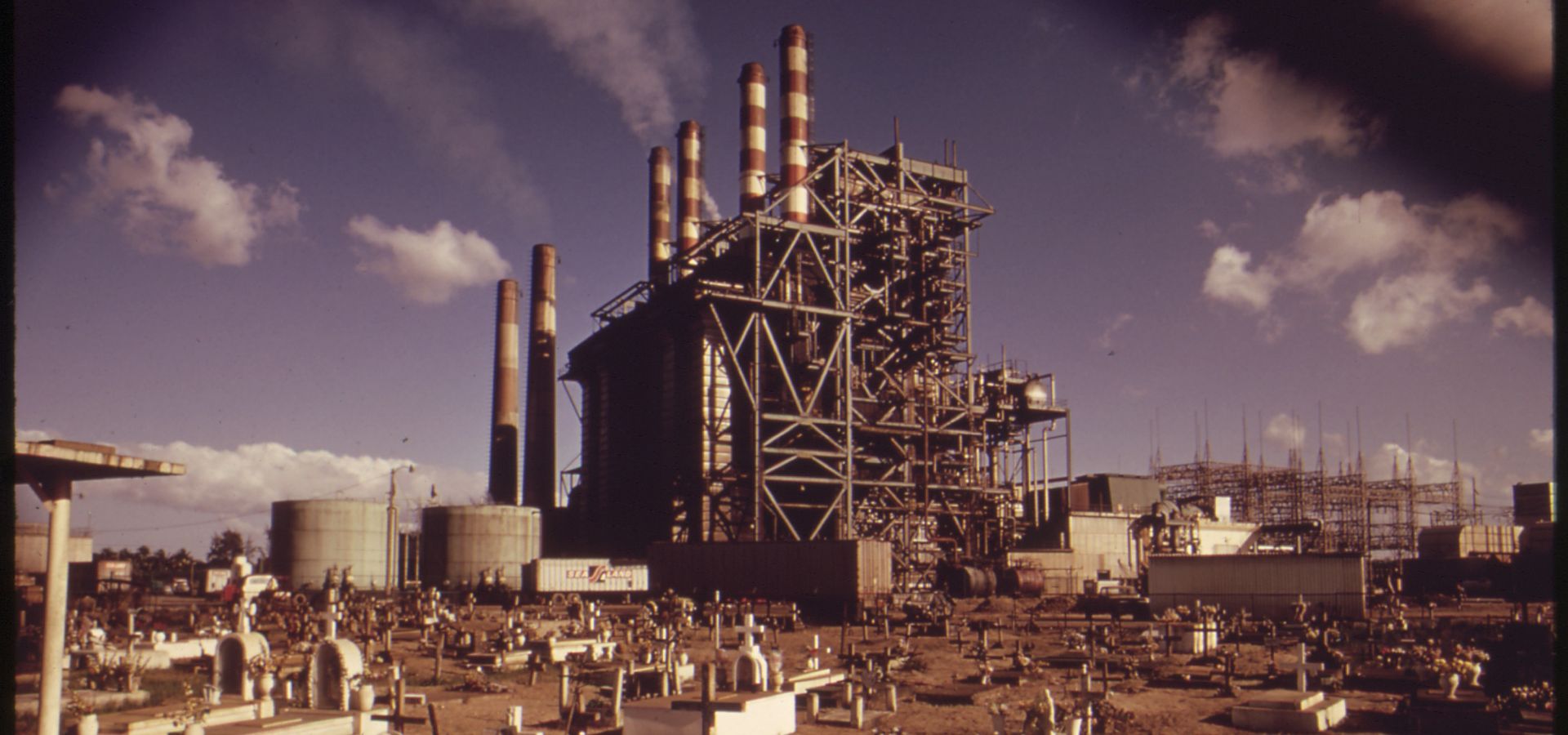 an old picture from the 1970s of a Puerto Rican power plant in the middle of a graveyard