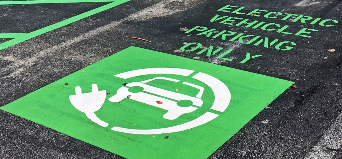 sign reading "electric vehicle parking only" in bright green at a charging station at a Mall in Miami, USA.