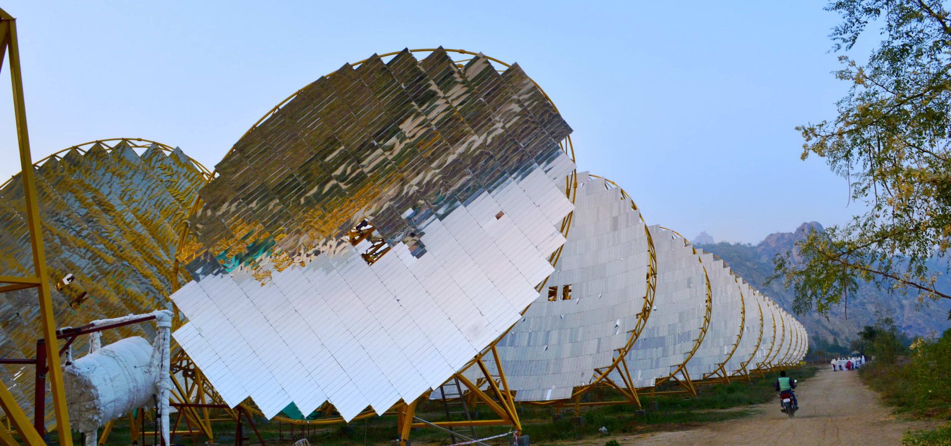 large circular solar panels from the India One solar plant, with mountains on the horizon