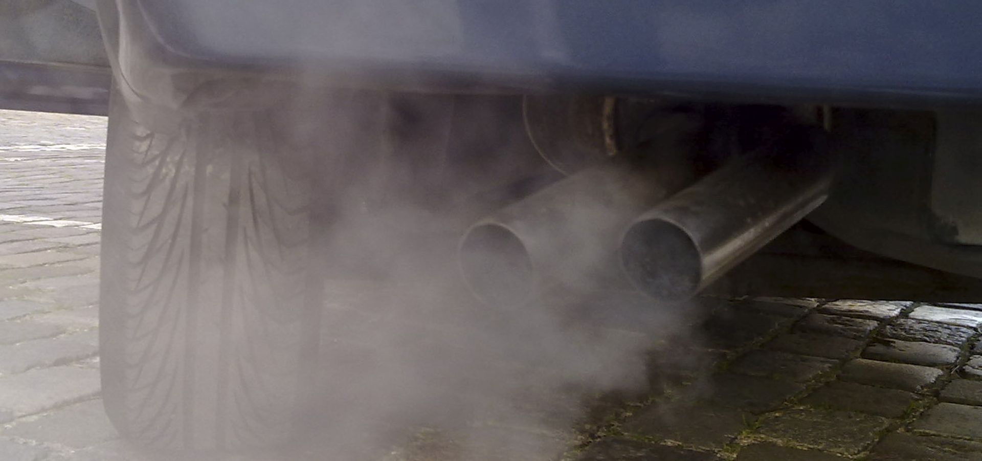 close up of car exhaust pipe with gray cloud