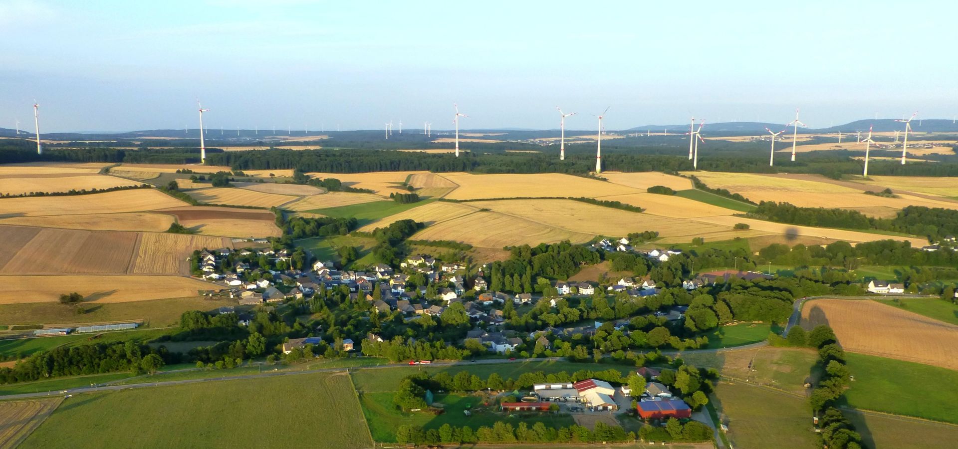 the village of Neuerkirch seen from above, surrounded by fields and wind turbines