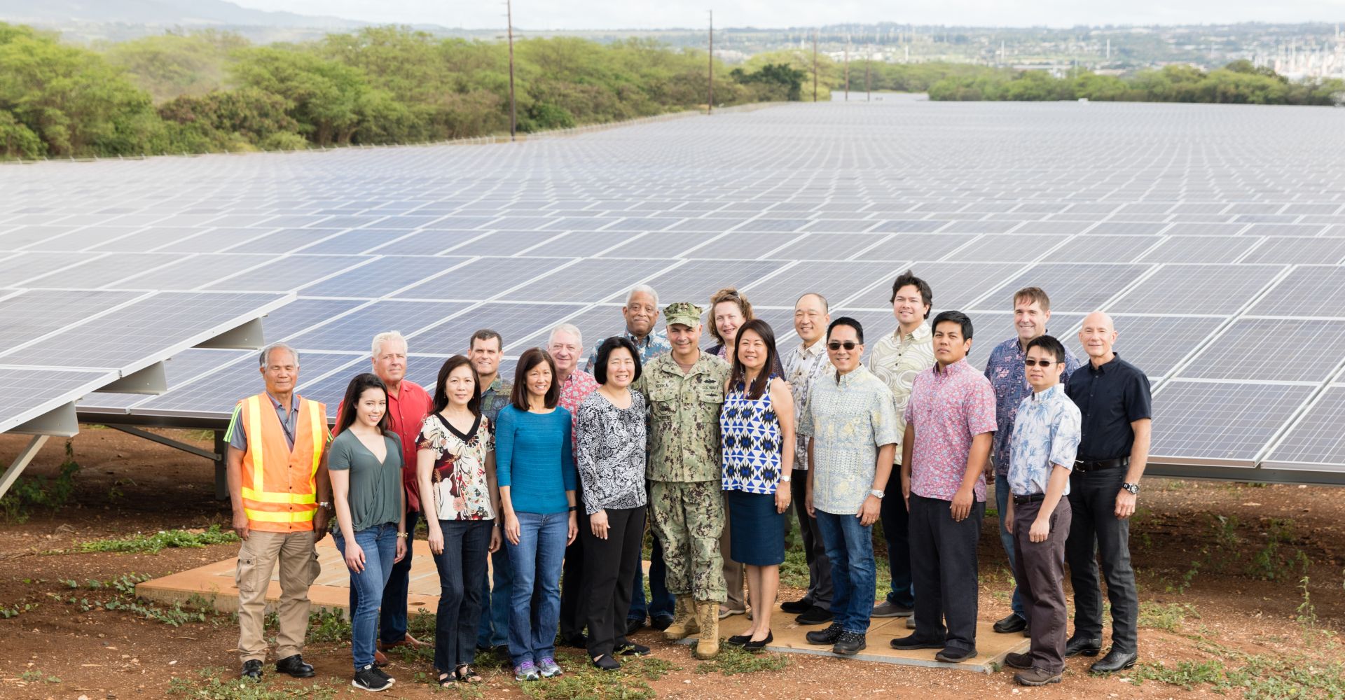 members of the Hawaii government, energy utility and military smiling in front of a large array of solar panels