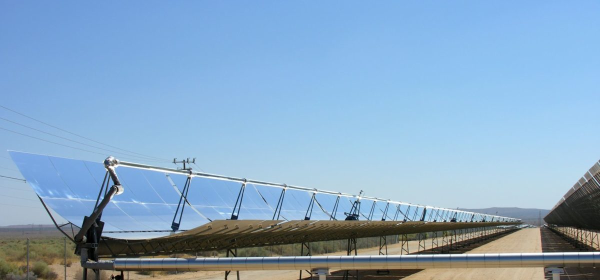 Solar trough reflecting a blue sky with desert in the background