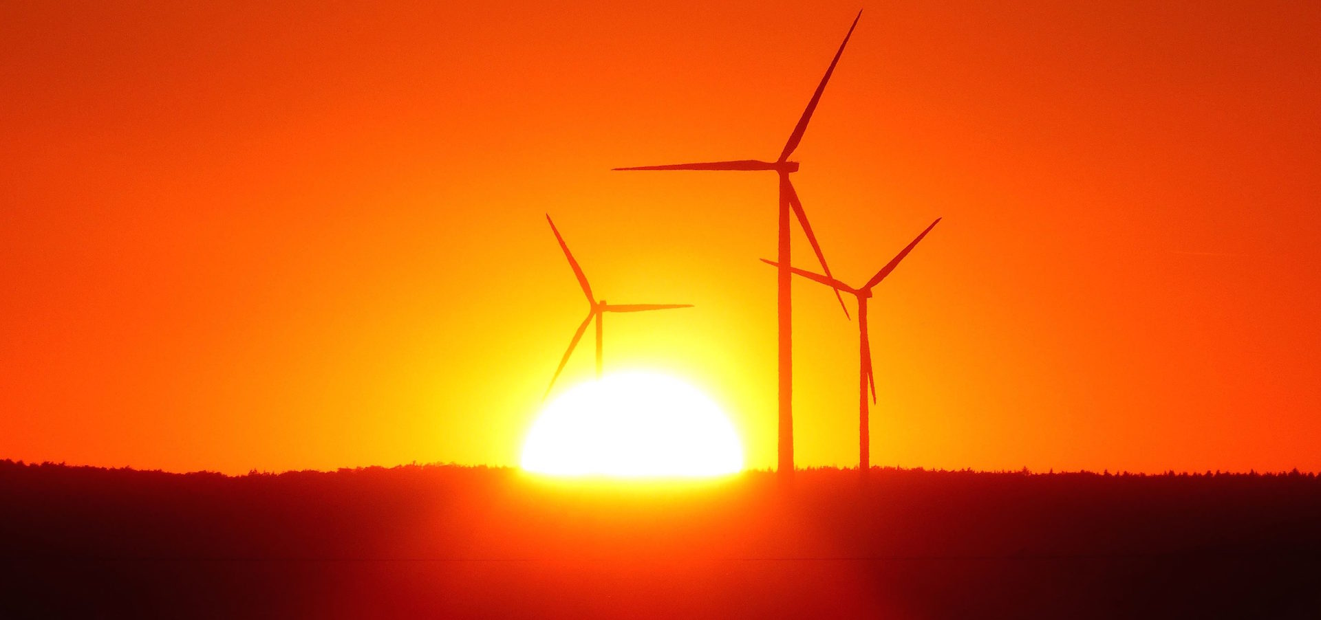 sunrise with three wind turbines in the foreground