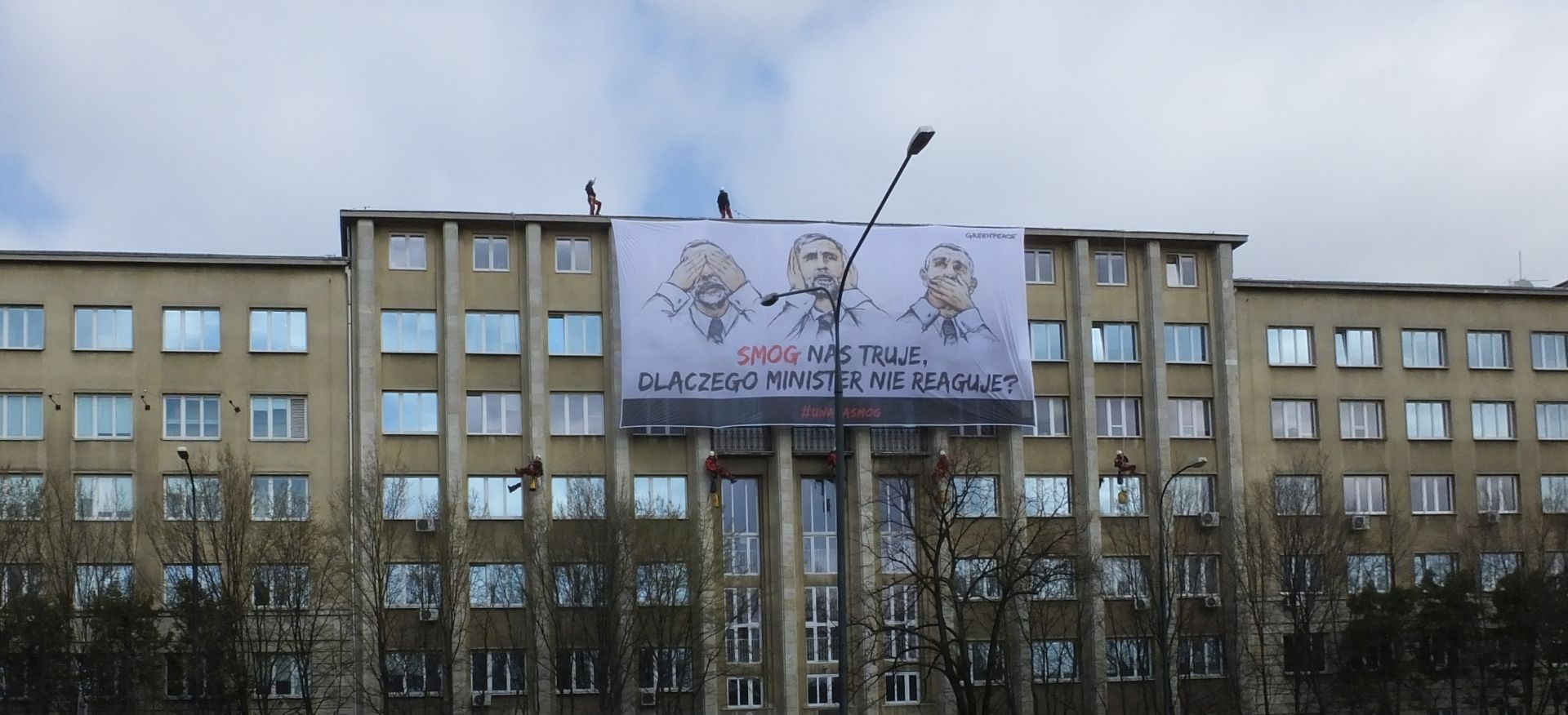 greenpeace action against smog - activists climb a building to hang a banner that says in polish that politicans are ignoring smog)