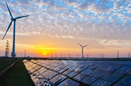 solar panels and wind turbines with sunrise reflecting on them